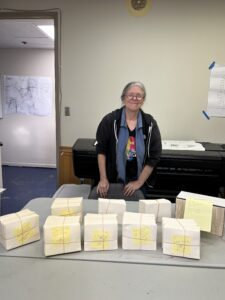Kathy Henley, Executive Director of ARROAutism, standing behind 773 Gift cards for the ARROAutism Family Holiday Assistance Project